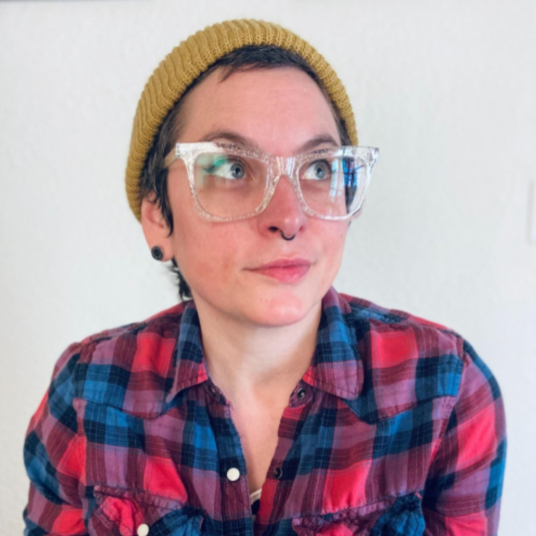 headshot of a white person with glasses and a flannel, looking off to the side
