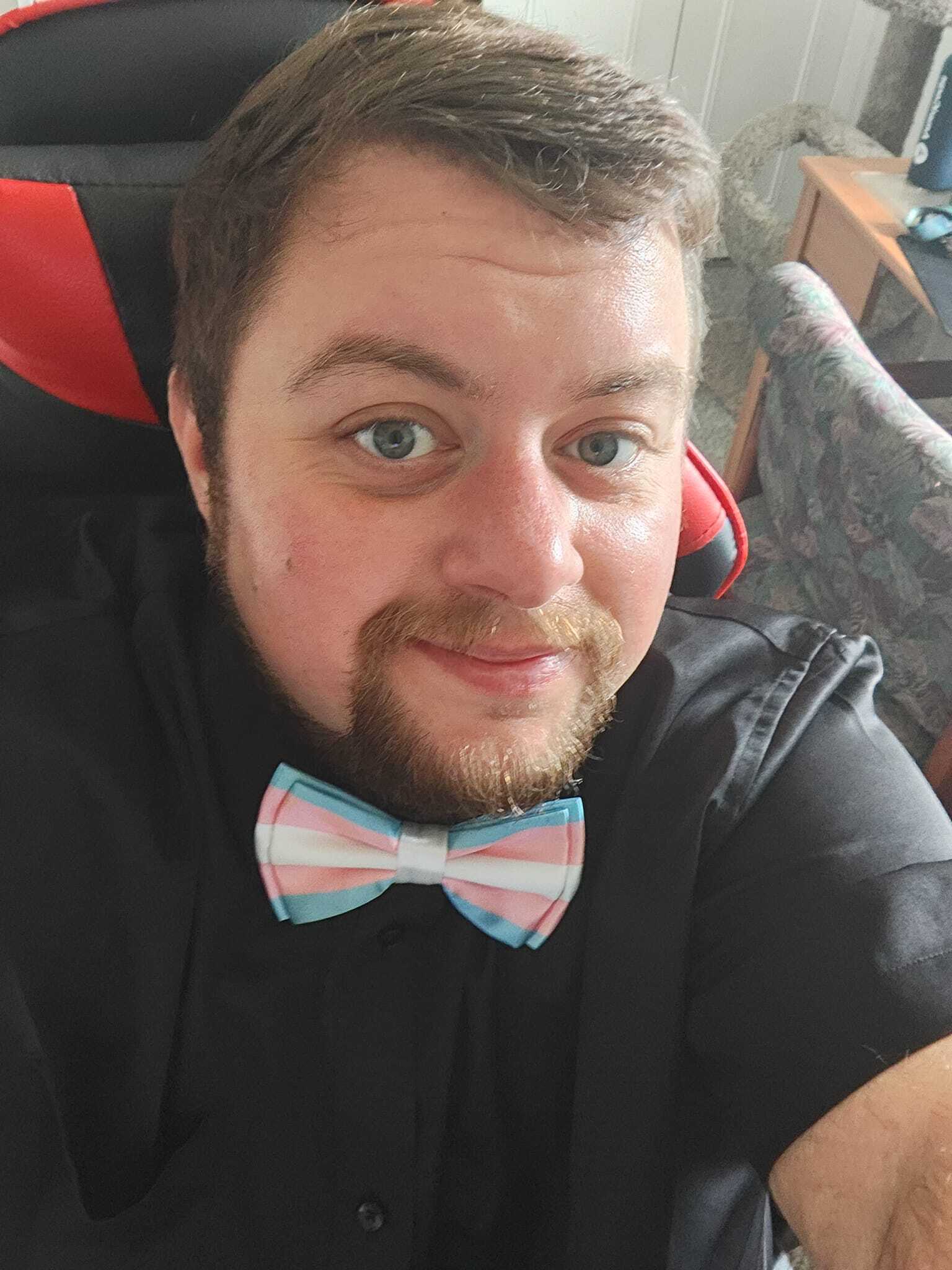 headshot of white man wearing a transgender flag bowtie