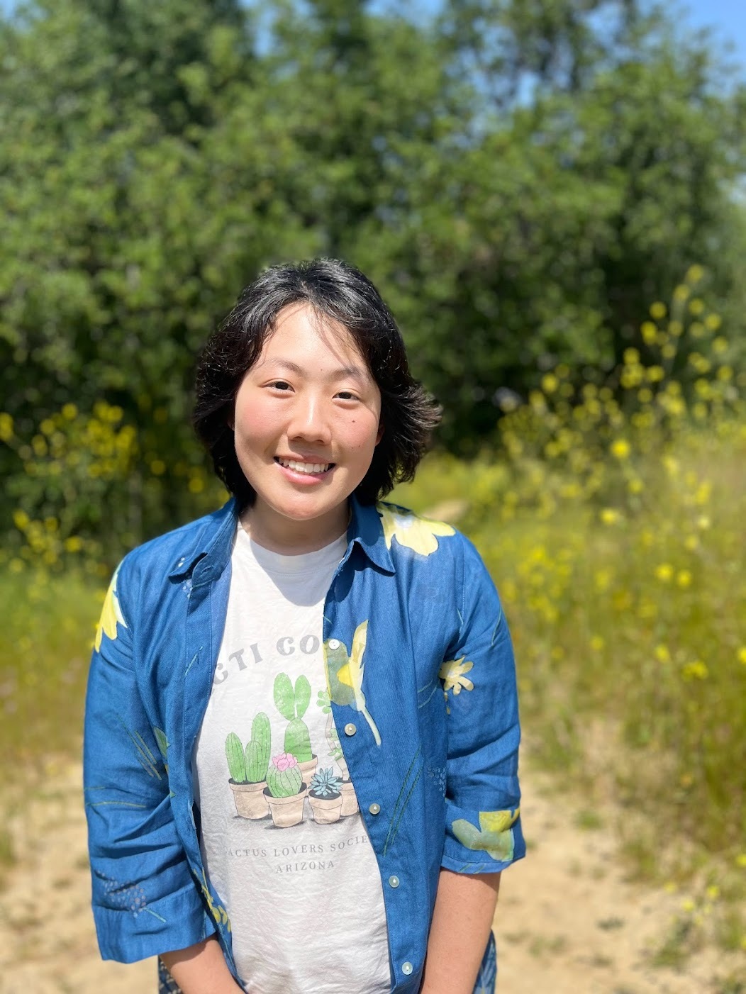 headshot of asian person in a field, they are smiling